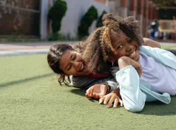 Two smiling Black girls laying on the grass